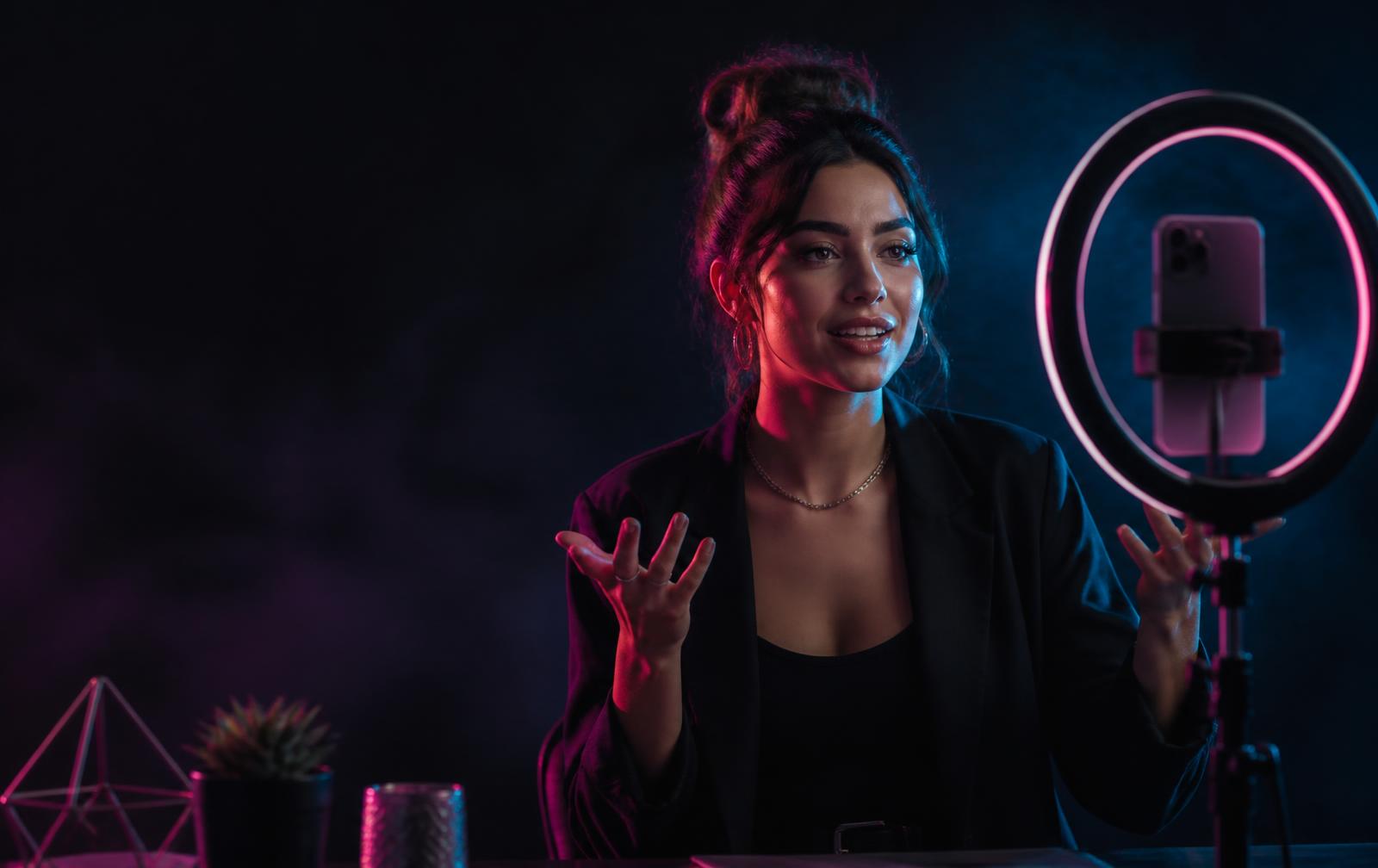 A creator broadcasting a TikTok LIVE stream under pink and cyan studio lighting